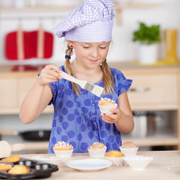 Kleines Mädchen garniert Cupcakes — Stockfoto