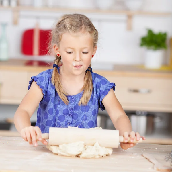 Girl using rolling pin on dough — Stock Photo, Image