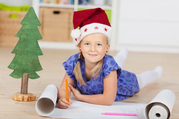 Meisje in Kerstman hoed puttend uit grafiek — Stockfoto