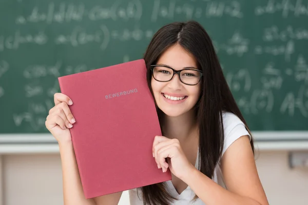 Happy college student holding up a red file — Stock Photo, Image