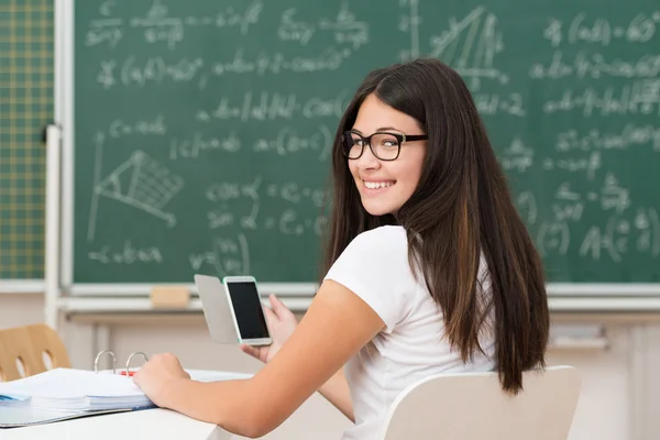 Lachende jonge vrouw in klasse met een mobiele — Stockfoto