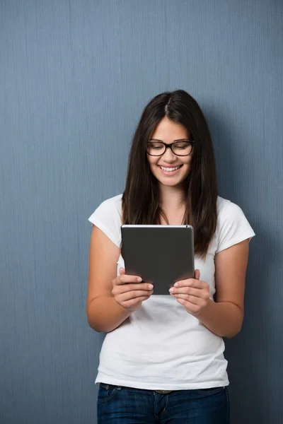 Menina muito jovem sorrindo como ela lê seu tablet — Fotografia de Stock