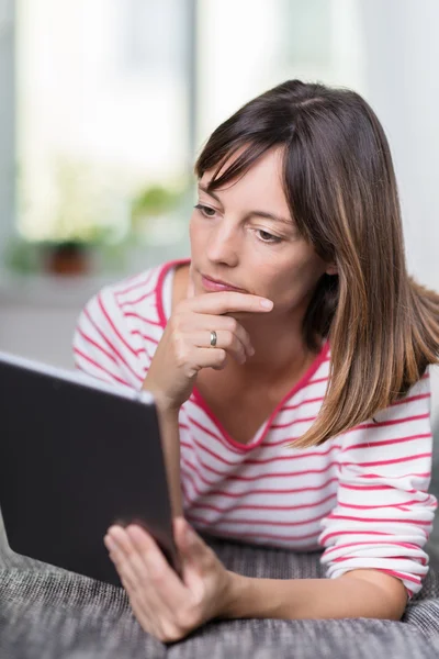 Femme réfléchie lisant sur une tablette — Photo