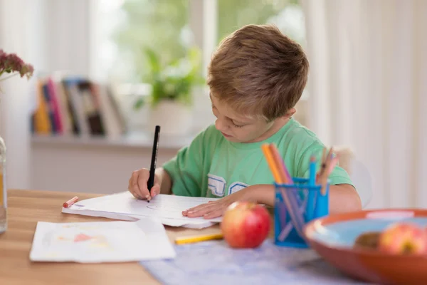 Młody chłopak w szkole ciężko pracuje na swoje notatki — Zdjęcie stockowe