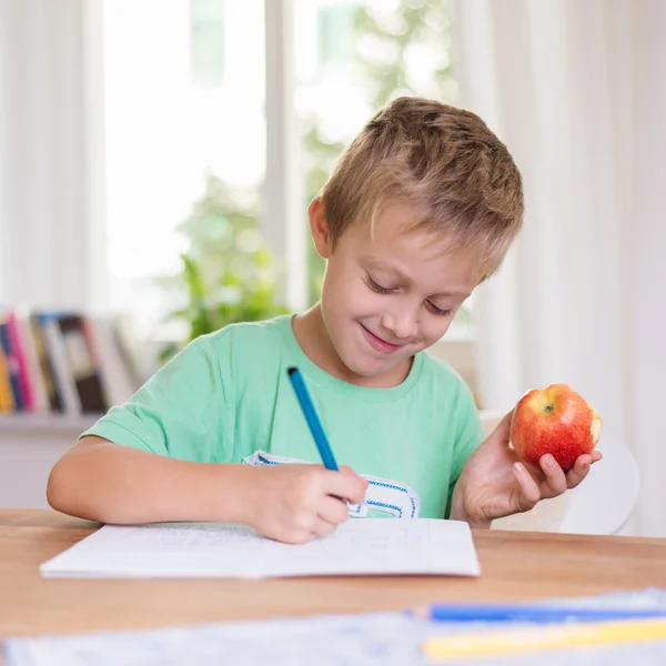 Rapaz feliz fazendo trabalhos escolares — Fotografia de Stock