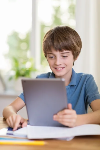 Мальчик улыбается, читая свой планшет — стоковое фото