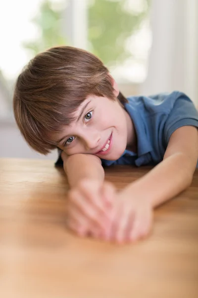 Niño feliz relajándose en una mesa de madera — Foto de Stock