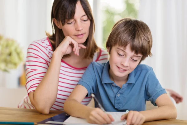 Junge Mutter hilft ihrem Sohn bei den Hausaufgaben — Stockfoto