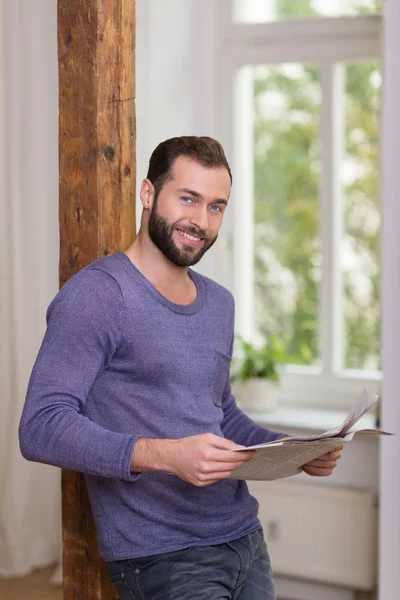 Friendly bearded man relaxing with a newspaper — Stock Photo, Image