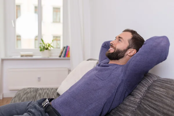 Успешный человек отдыхает на диване дома — стоковое фото