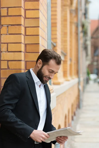 Businessman standing outdoors reading — Stock Photo, Image