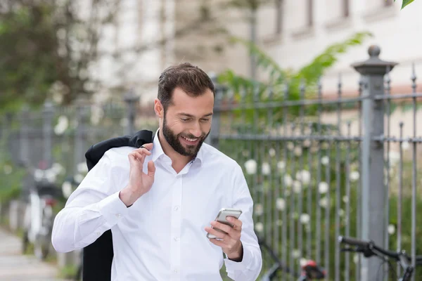 Sorridente bell'uomo che usa il telefono mentre cammina — Foto Stock