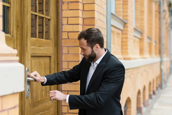 Empresário que abre a porta de um edifício — Fotografia de Stock