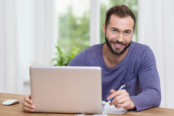 Un hombre de negocios sonriente trabajando en un portátil — Foto de Stock