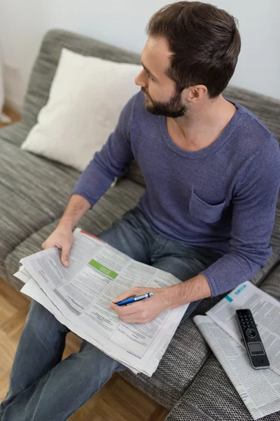 Man reading the newspaper on a sofa — Stock Photo, Image