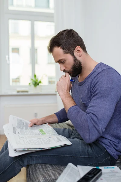 Un hombre pensativo sentado leyendo un periódico — Foto de Stock