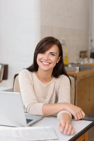 Χαμογελώντας νεαρή γυναίκα που κάθεται σε ένα γραφείο — Φωτογραφία Αρχείου