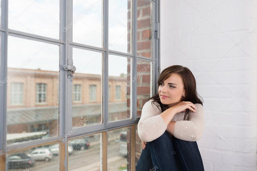Entspannte Frau schaut aus dem Fenster Stockfotografie