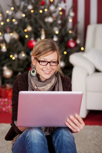 Kobieta z laptopa w przednim choinki — Zdjęcie stockowe