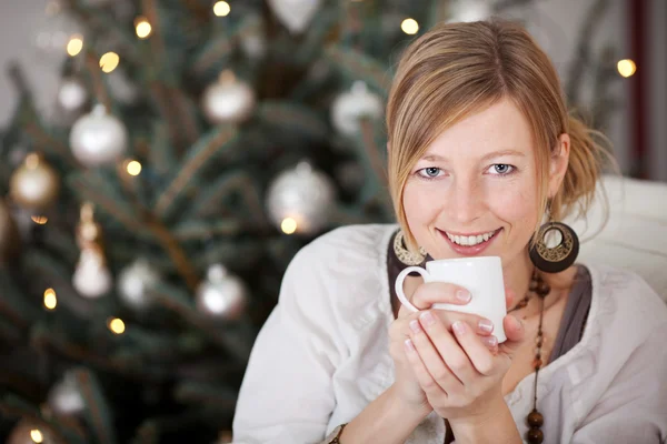 Woman with coffee beside christmas tree — Stock Photo, Image