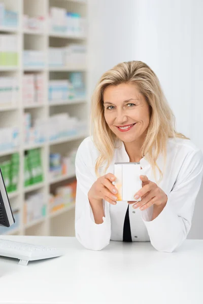 Middle-aged pharmacist displaying box — Stock Photo, Image