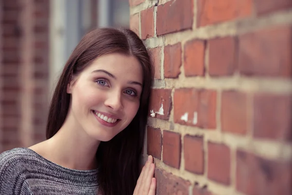 Mujer apoyada en la pared de ladrillo — Foto de Stock