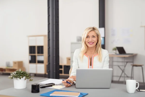 Счастливая деловая женщина за столом с ноутбуком — стоковое фото