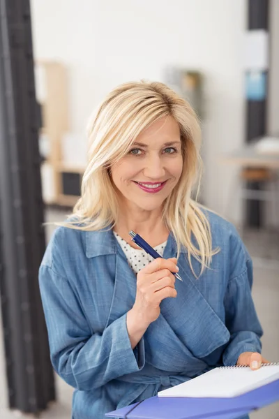 Smiling woman sitting taking notes — Stockfoto