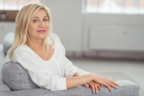 Erwachsene Frau sitzt auf grauem Sofa — Stockfoto