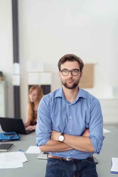 Hombre de negocios guapo apoyado contra la mesa — Foto de Stock