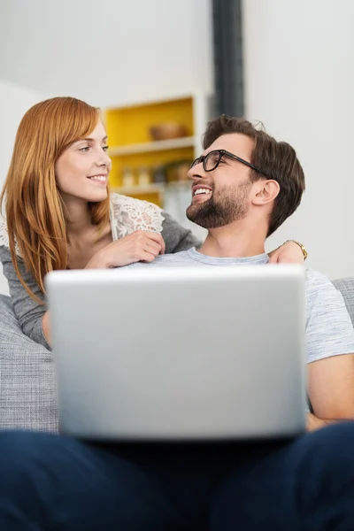 Casal com laptop sorrindo um para o outro — Fotografia de Stock