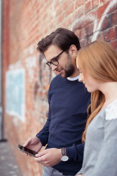 Couple with Smart Phone Leaning Against Brick Wall — Stock Photo, Image