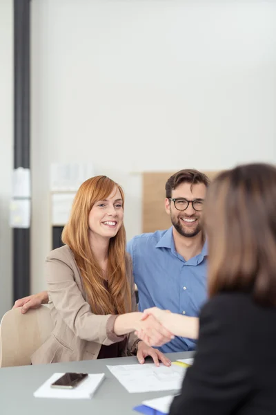 Pareja joven llegando a un acuerdo con un corredor — Foto de Stock