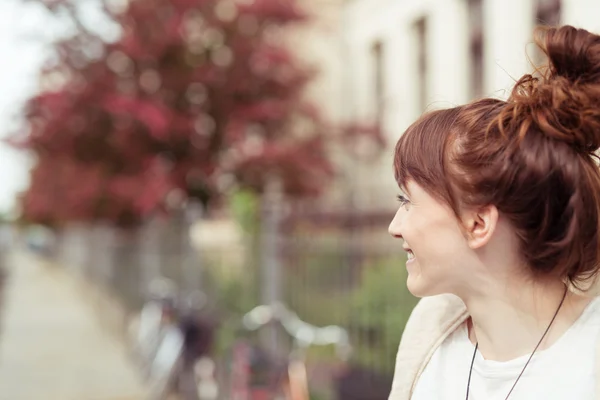 Redhead woman smiling as she waits on a street — Φωτογραφία Αρχείου