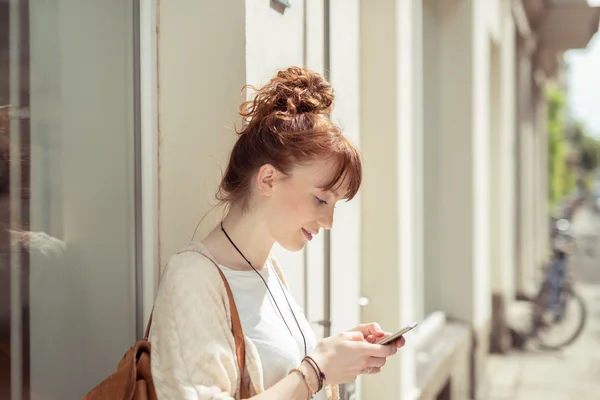 Jonge vrouw lezen een sms op haar mobiele telefoon — Stockfoto