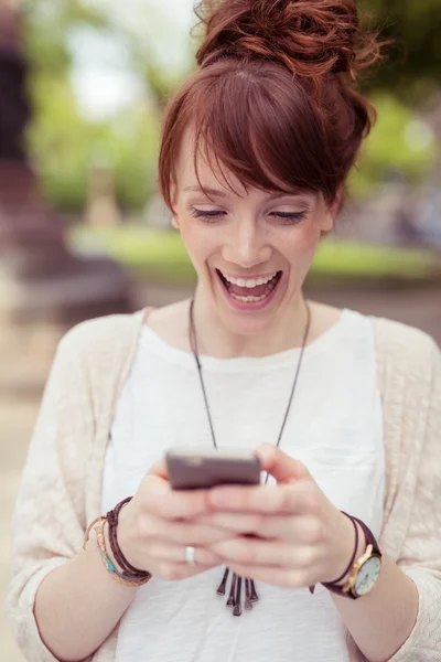 Encantada joven leyendo un sms en su móvil — Foto de Stock