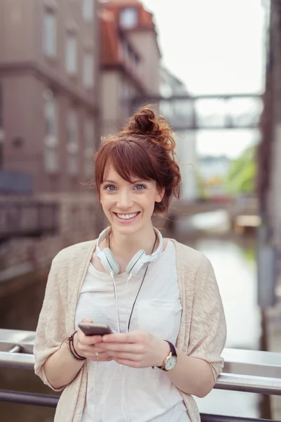 Veselá dívka drží telefon na zábradlí — Stock fotografie