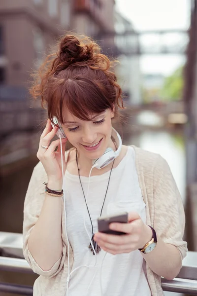 Девочка слушает музыку на своем телефоне в наушниках — стоковое фото