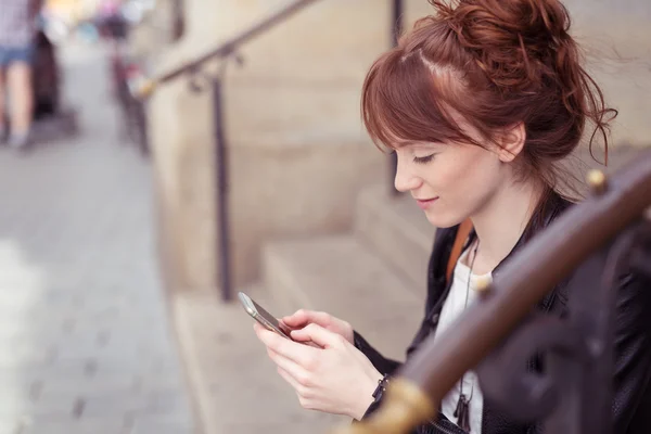 Pretty woman sitting on steps to read an sms — Stock Photo, Image