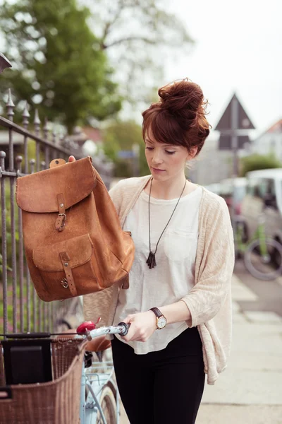 Mujer poniendo su bolsa en una cesta de bicicleta —  Fotos de Stock
