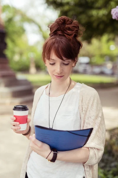 Attraktives Mädchen liest etwas mit Kaffeetasse — Stockfoto