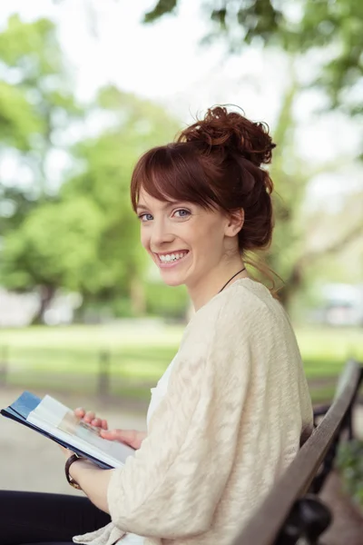 Junge Frau entspannt auf einer Parkbank — Stockfoto