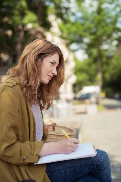 Bella ragazza pensando a cosa scrivere sui suoi appunti — Foto Stock