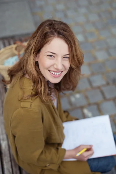 Diligente chica en banco al aire libre mirando a la cámara — Foto de Stock