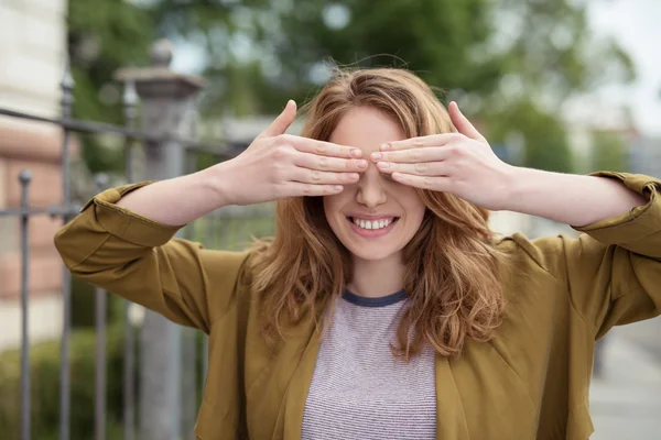 Fröhliches Teenie-Mädchen, das seine Augen mit Händen bedeckt — Stockfoto