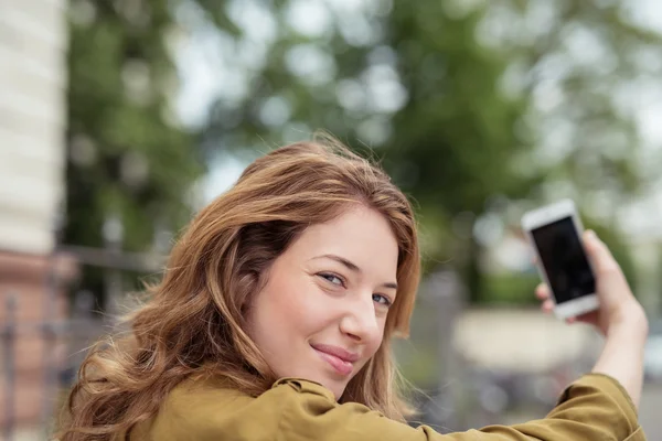Bella ragazza guardando fotocamera mentre prende selfie — Foto Stock