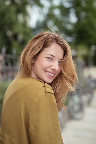 Menina bonita feliz olhando para a câmera de suas costas — Fotografia de Stock