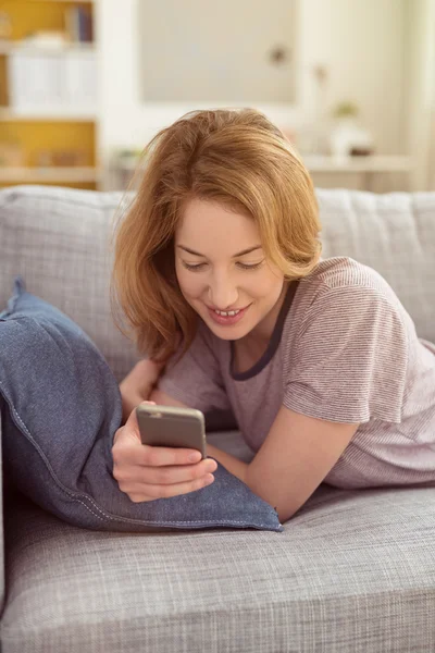 Усміхнена молода жінка перевіряє текстові повідомлення — стокове фото