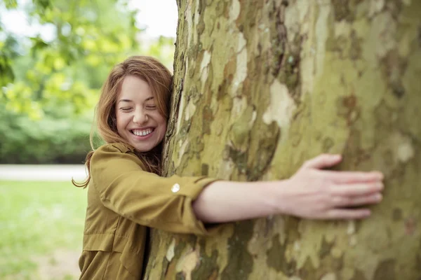 Glada teen flicka kramar enorma trädstammen — Stockfoto