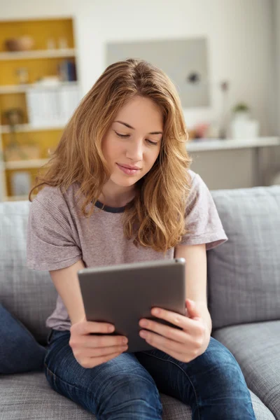 Девочка-подросток сидит на диване с планшетным компьютером — стоковое фото